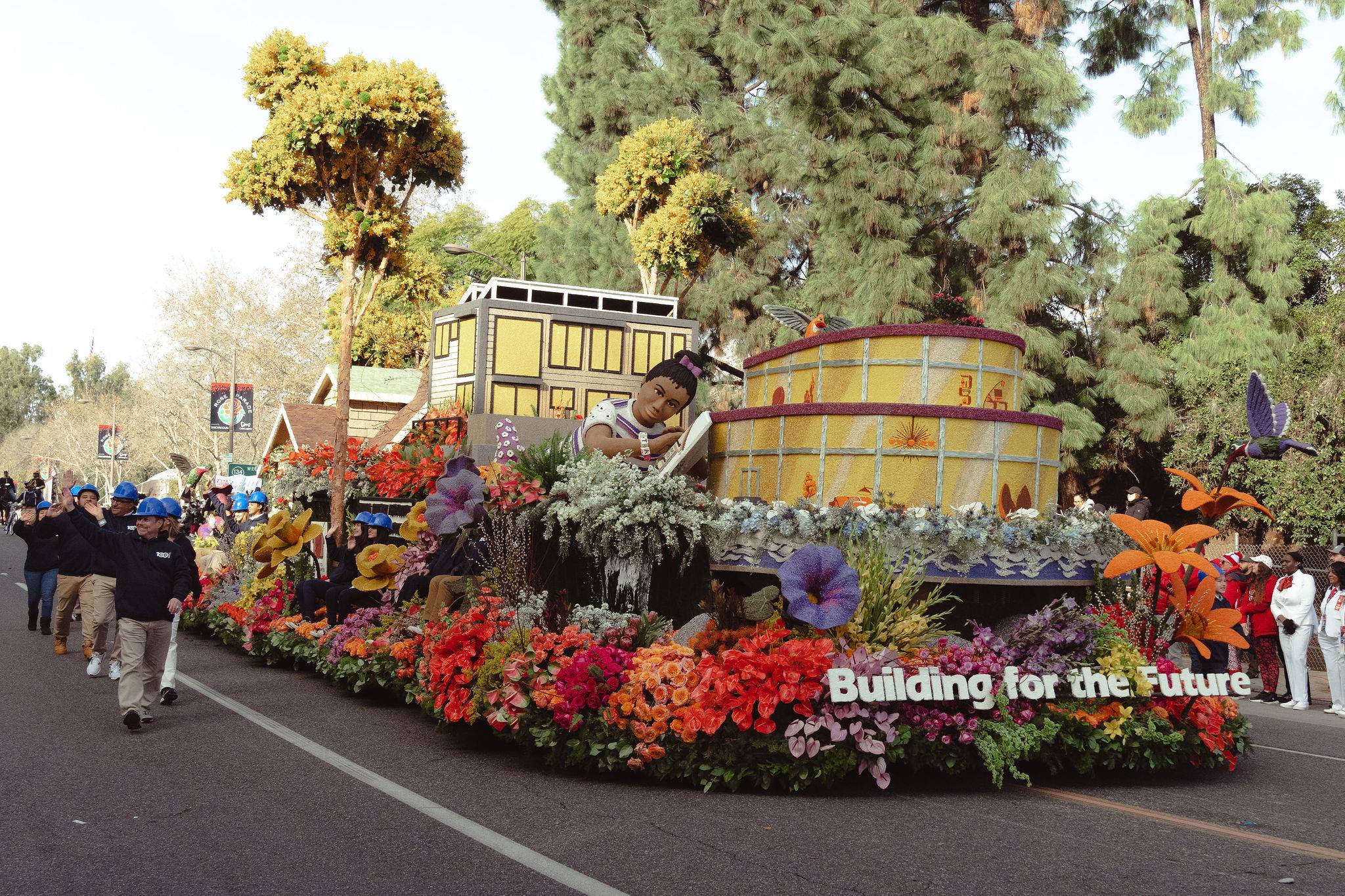 Building industry float at the Rose Parade with colorful flowers and "Building for the Future" sign.