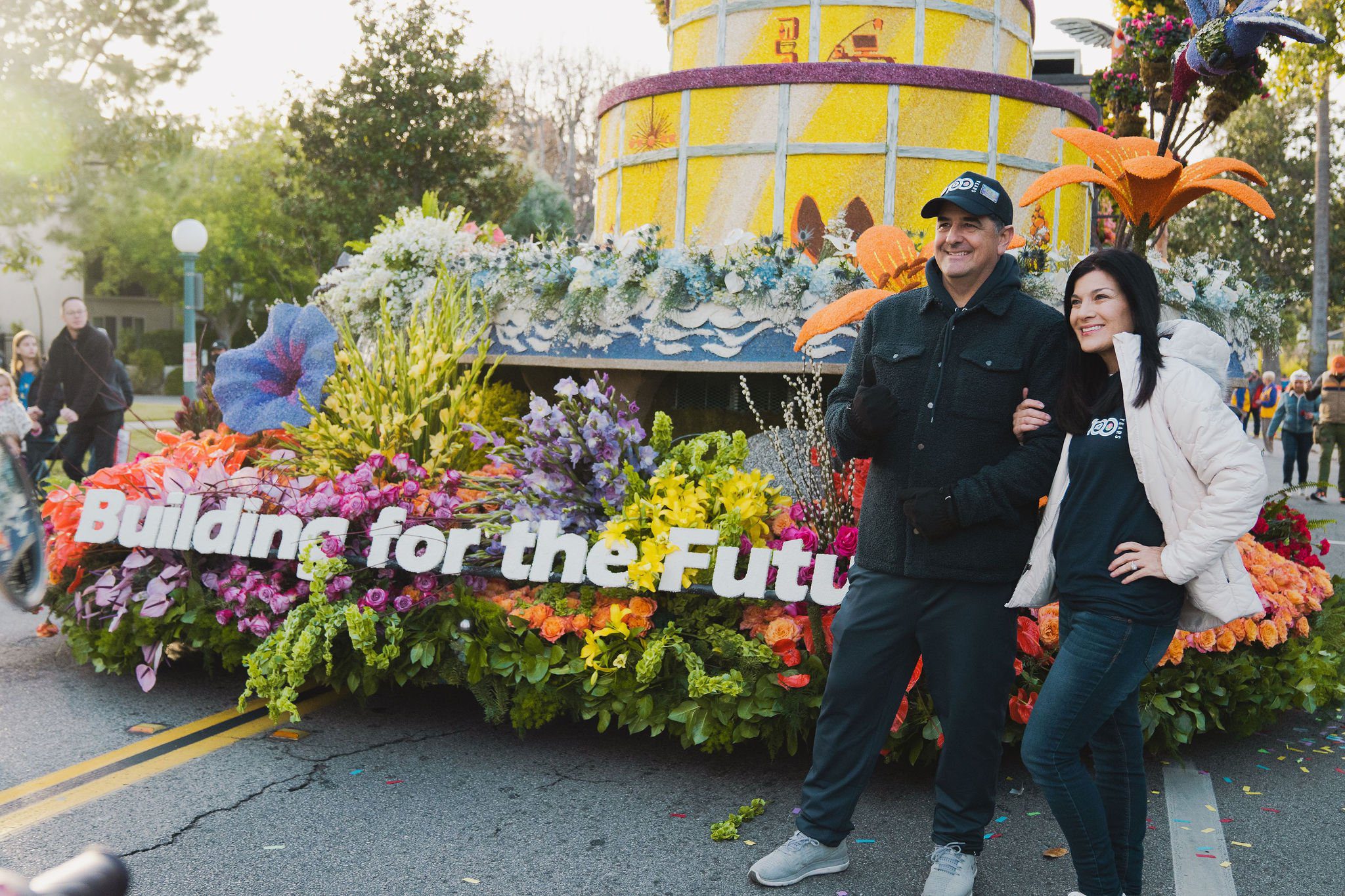 BIASC participants in front of the 'Building for the Future' float at the Rose Parade, surrounded by vibrant flowers.