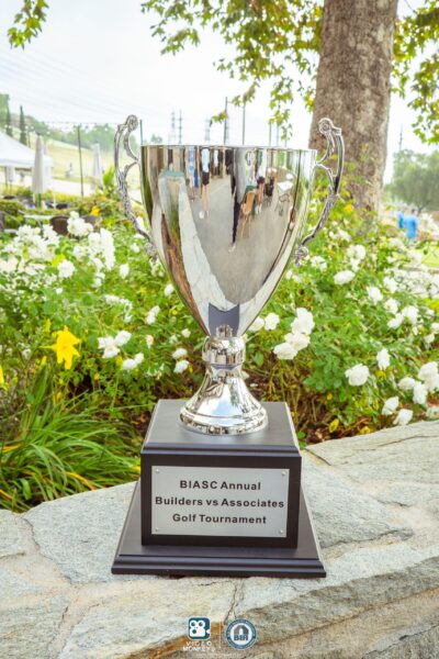BIASC Annual Builders vs Associates Golf Tournament trophy. BIASC Annual Builders vs Associates Golf Tournament trophy displayed outdoors with flowers in the background.
